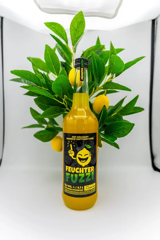 Flasche vor einem Zitronenbäumchen auf weißem Grund