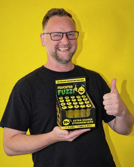 Lars Ehrhardt hält das Feuchter-Fuzzi-Partypack und zeigt den Daumen nach oben