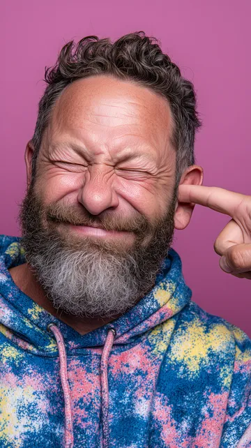 Lachender Mann mit einem Finger im Ohr